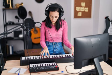 Foto de Joven mujer caucásica músico tocando el piano en estudio de música - Imagen libre de derechos