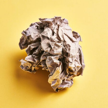 Photo for One brown crumpled paper ball over isolated yellow background - Royalty Free Image