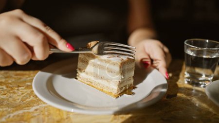 Téléchargez les photos : Une femme profite d'un dessert délicieux dans un café, ses mains soignées ajoutant de l'élégance à l'indulgence. - en image libre de droit
