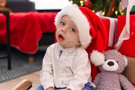 Téléchargez les photos : Adorable bambin blond assis sur le sol par des cadeaux de Noël à la maison - en image libre de droit