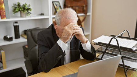Téléchargez les photos : Homme âgé surmené se sentant stressé, travaillant sur un ordinateur portable au bureau - en image libre de droit
