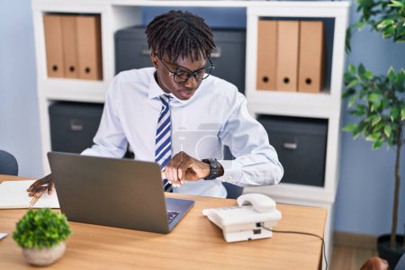 Téléchargez les photos : Africain américain homme d'affaires en utilisant un ordinateur portable regarder au bureau - en image libre de droit