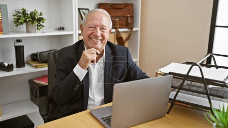 Photo for Confident senior man joyfully working on laptop at business office, exuding confidence and success - Royalty Free Image