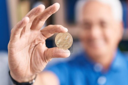 Photo for Middle age grey-haired man holding litecoin crypto currency at home - Royalty Free Image