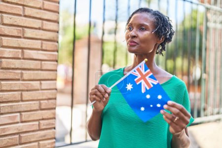 Photo for Middle age african american woman smiling confident holding australia flag at street - Royalty Free Image