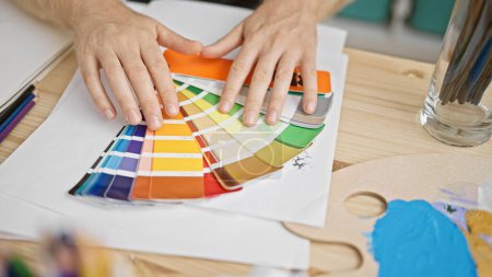 Téléchargez les photos : Gros plan des mains sélectionnant un échantillon de couleur dans une palette, ce qui indique une planification du design d'intérieur ou un travail artistique. - en image libre de droit