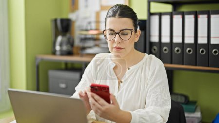 Photo for Young beautiful hispanic woman business worker using laptop and smartphone at the office - Royalty Free Image