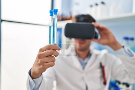Photo for Young hispanic man scientist using virtual reality glasses holding test tubes at laboratory - Royalty Free Image