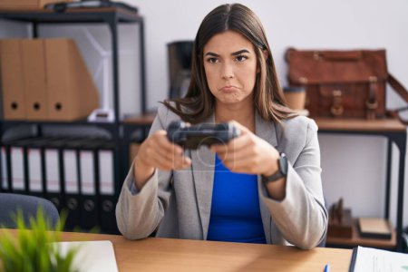 Foto de Mujer hispana que trabaja en la oficina jugando videojuegos deprimida y preocupada por la angustia, llorando enojada y asustada. expresión triste. - Imagen libre de derechos