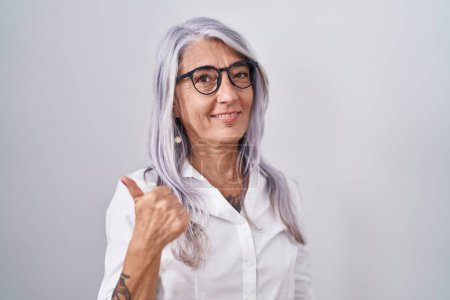 Photo for Middle age woman with tattoos wearing glasses standing over white background doing happy thumbs up gesture with hand. approving expression looking at the camera showing success. - Royalty Free Image