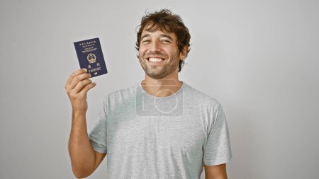 Téléchargez les photos : Jeune homme éclatant de joie tient son passeport pour hong kong, exsudant confiance et bonheur sur un fond blanc immaculé - en image libre de droit