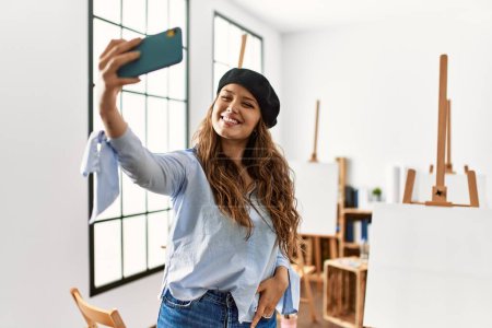 Téléchargez les photos : Jeune belle artiste hispanique femme faire selfie par smartphone au studio d'art - en image libre de droit