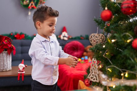 Foto de Adorable niño hispano decorando el árbol de Navidad en casa - Imagen libre de derechos