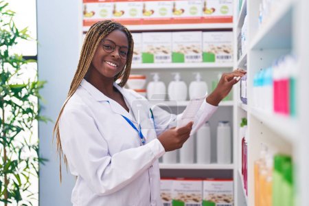 Foto de Farmacéutica afroamericana leyendo prescripción en farmacia - Imagen libre de derechos
