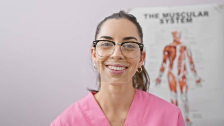 Foto de Mujer hispana joven confiada y hermosa sonriendo mientras está lista para la fisioterapia en una clínica de rehabilitación, un retrato del servicio médico alegre - Imagen libre de derechos
