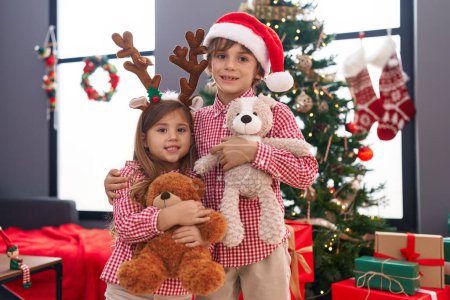 Téléchargez les photos : Frère et sœur s'embrassant debout par des cadeaux de Noël à la maison - en image libre de droit