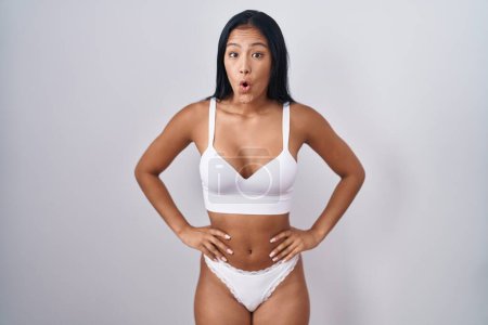 Photo for Hispanic woman wearing lingerie afraid and shocked with surprise and amazed expression, fear and excited face. - Royalty Free Image