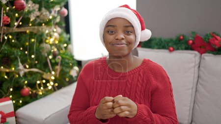 Téléchargez les photos : Femme afro-américaine souriante confiante célébrant Noël à la maison - en image libre de droit