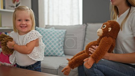 Téléchargez les photos : Bonne mère caucasienne et petite fille jouissant confortablement et jouant avec des jouets à la maison, reposant sur le canapé - en image libre de droit