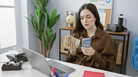 Photo for Young caucasian woman examines hungarian forint banknotes in an office, evoking finance and business themes. - Royalty Free Image