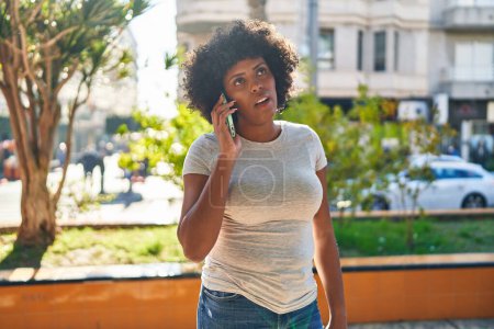Téléchargez les photos : Femme afro-américaine parlant sur smartphone avec une expression sérieuse au parc - en image libre de droit