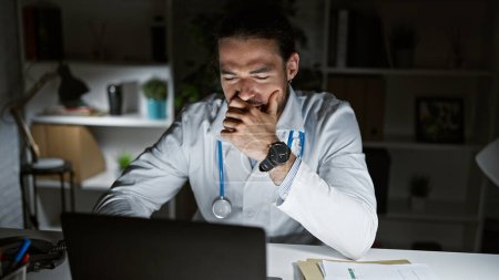 Photo for Young hispanic man doctor using laptop tired yawning at the clinic - Royalty Free Image