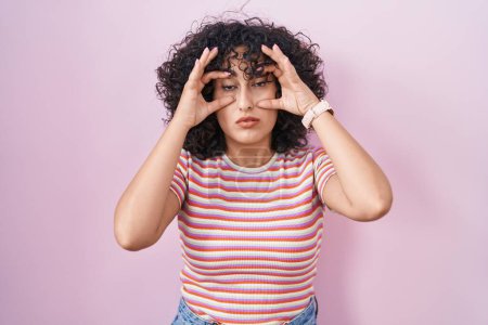 Photo for Young middle east woman standing over pink background trying to open eyes with fingers, sleepy and tired for morning fatigue - Royalty Free Image