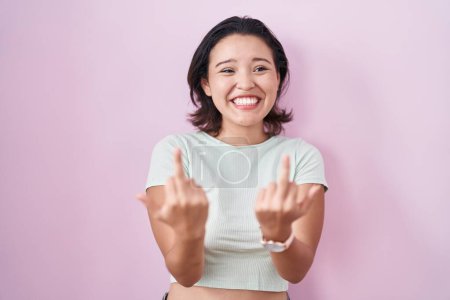 Foto de Hispanic young woman standing over pink background showing middle finger doing fuck you bad expression, provocation and rude attitude. screaming excited - Imagen libre de derechos