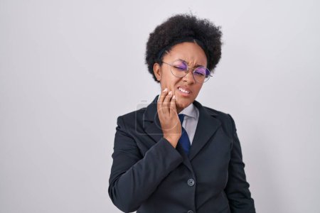 Téléchargez les photos : Belle femme africaine aux cheveux bouclés portant une veste d'affaires et des lunettes touchant la bouche à la main avec une expression douloureuse à cause de maux de dents ou de maladies dentaires sur les dents. dentiste - en image libre de droit