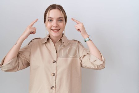 Foto de Mujer caucásica joven con camisa casual sonriendo apuntando a la cabeza con ambas manos dedo, gran idea o pensamiento, buena memoria - Imagen libre de derechos