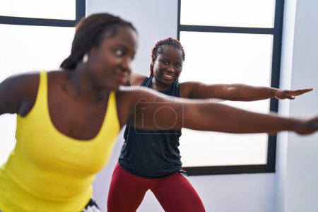 Foto de Mujeres afroamericanas sonriendo yoga de entrenamiento seguro en el centro deportivo - Imagen libre de derechos