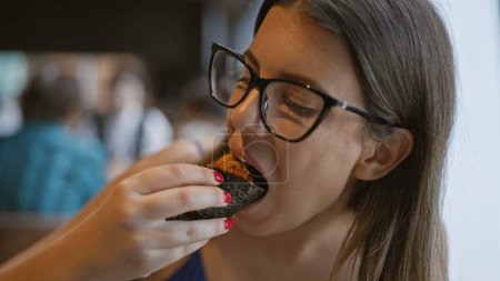 Photo for Gorgeous hispanic woman savoring exquisite uni sushi, a culinary feast of japanese seafood delicacy in chic restaurant - Royalty Free Image