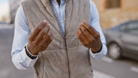 Téléchargez les photos : Homme afro-américain en gilet gestuel en plein air dans un cadre urbain de rue. - en image libre de droit