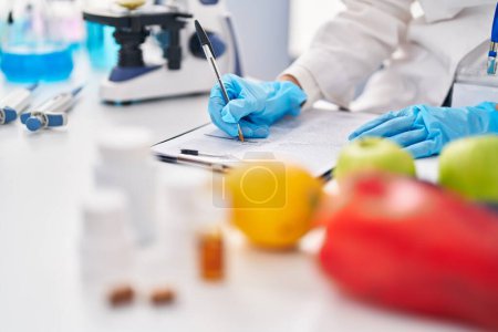 Photo for Young beautiful hispanic woman scientist writing food and pills report at laboratory - Royalty Free Image