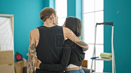 Foto de Hermosa pareja de pie hacia atrás abrazándose en casa nueva - Imagen libre de derechos
