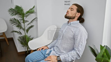 Téléchargez les photos : Jeune homme hispanique assis sur une chaise avec un visage sérieux stressé dans la salle d'attente - en image libre de droit
