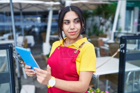 Photo for Young beautiful arab woman waitress smiling confident using touchpad at coffee shop terrace - Royalty Free Image