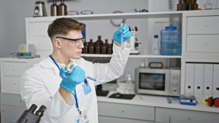 Photo for Handsome, bearded young caucasian man, a devoted scientist, measuring liquid meticulously in test tube, working indoors at the buzzing chemistry lab - Royalty Free Image
