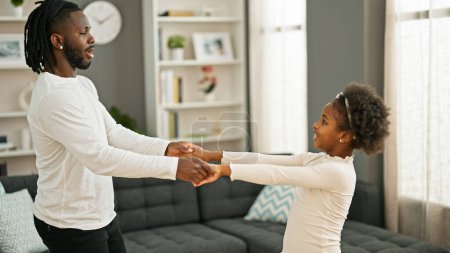Téléchargez les photos : Afro-américain père et fille souriant danse confiante à la maison - en image libre de droit