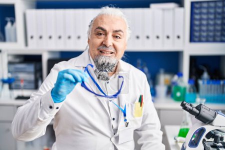 Photo for Middle age grey-haired man scientist smiling confident holding security glasses at laboratory - Royalty Free Image