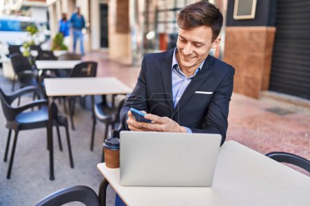 Photo for Young man business worker using laptop and smartphone at coffee shop terrace - Royalty Free Image