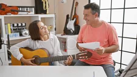 Photo for Smiling male and female musicians engrossed in a classic guitar lesson at a cozy music studio, sharing their love for music. - Royalty Free Image