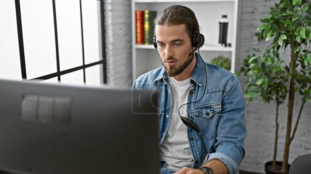 Téléchargez les photos : Jeune homme hispanique travailleur d'affaires en utilisant l'ordinateur et les écouteurs au bureau - en image libre de droit