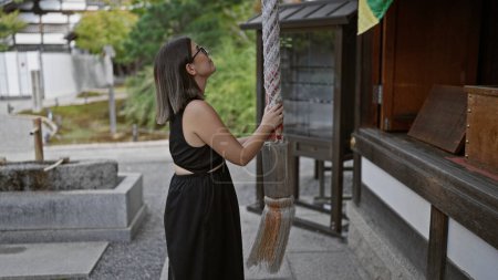 Téléchargez les photos : Scène kyoto moment, belle femme hispanique dans des lunettes tire la corde pour frapper la cloche au temple kodaiji - en image libre de droit