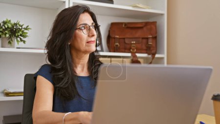 Photo for Professional hispanic woman working on laptop in modern office - Royalty Free Image