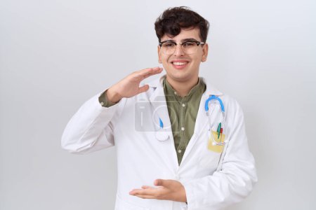 Photo for Young non binary man wearing doctor uniform and stethoscope gesturing with hands showing big and large size sign, measure symbol. smiling looking at the camera. measuring concept. - Royalty Free Image