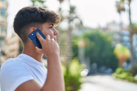 Photo for Young hispanic teenager talking on smartphone with relaxed expression at street - Royalty Free Image