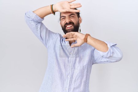 Téléchargez les photos : Homme hispanique avec barbe portant chemise décontractée souriant gai jouer jeter un coup d'oeil un boo avec les mains montrant le visage. surpris et sortis - en image libre de droit