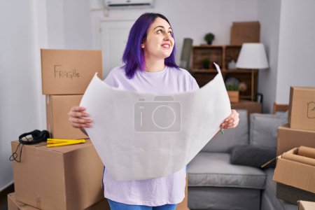 Photo for Young beautiful plus size woman architect smiling confident reading house plans at new home - Royalty Free Image