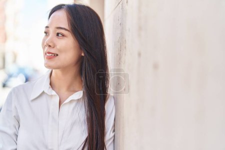 Foto de Joven mujer china sonriendo confiada mirando a un lado en la calle - Imagen libre de derechos